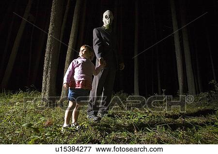 Stock Photo - Man in gas mask with little girl at night in forest, Cypress Hill, Saskatchewan, Canada. Fotosearch