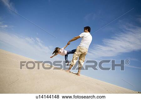 Stock Photo - Man swings girl (4) in circle, Grand Beach Provincial Park, Manitoba, Canada. Fotosearch