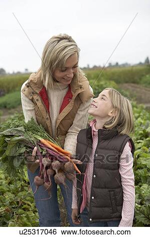Stock Photograph - Mother and daughter at an organic farm with fresh vegetables, Ladner, British Columbia, Canada. Fotosearch