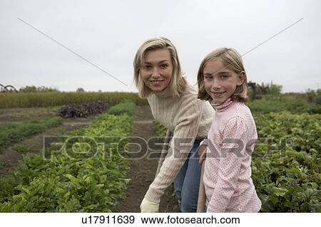 Stock Photo - Mother and daughter gardening together in organic garden, Ladner, British Columbia, Canada. Fotosearch