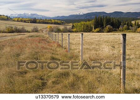 Fence through rural farmland with snowcapped mountains in the background, Clinton, BC, Canada View Large Photo Image Stock Photo - Fence through rural farmland with snowcapped mountains in the background, Clinton, BC, Canada. Fotosearch