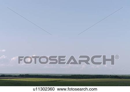 Stock Image - Vista of green fields and distant hills; Canada, Manitoba, Erickson. Fotosearch