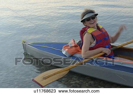 Stock Image - 45 year old woman kayaking on clear Lake; Canada, Manitoba, Riding Mountain National Park. Fotosearch