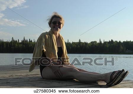 Stock Photography - 45 year old woman on dock, no motors allowed on lake.; Canada, Manitoba, Riding Mountain National Park. Fotosearch