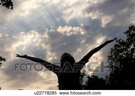 Stock Photography - Girl with arms upstretched toward sunset, Assiniboine Park, Winnipeg, Canada. Fotosearch