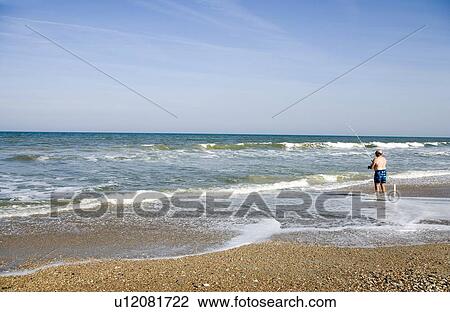 Stock Image - Man fishing in the ocean, Jacksonville, Florida. Fotosearch