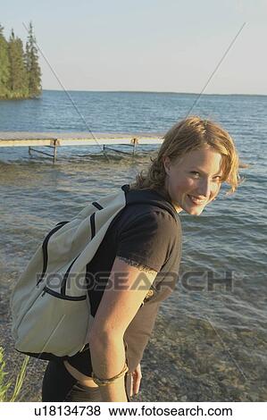 Stock Photo - Smiling woman at lakeshore, Clear Lake, Riding Mountain National Park, Manitoba, Canada. Fotosearch