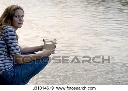 Stock Photo - Twelve year old girl holds water sample beside Assiniboine River, Winnipeg, Canada. Fotosearch