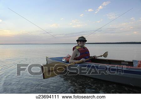 Stock Image - Woman in kayak Clear Lake Riding Mt. Nat. Park; Canada, Manitoba, Riding Mountain National Park. Fotosearch