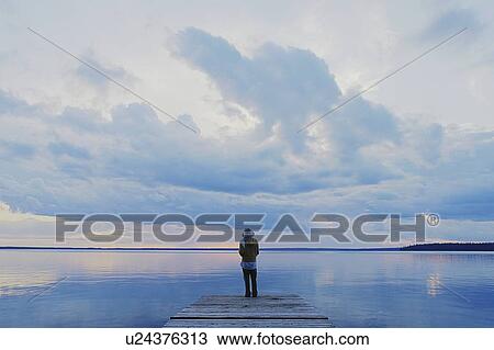 Stock Image - Woman on public dock Clear Lake; Canada, Manitoba, Riding Mountain National Park. Fotosearch