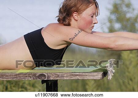 Stock Photo - Woman on stomach, stretching forward, Grayling Lake, Riding Mountain National Park, Manitoba, Canada. Fotosearch