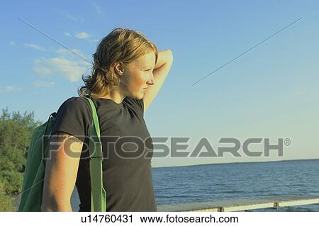 Stock Image - Woman with hemp satchel at lakeside, Clear Lake, Riding Mountain National Park, Manitoba, Canada. Fotosearch