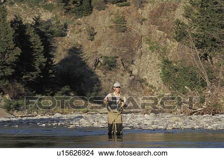 Picture - Young man fly fishing on Oldman river in southern Alberta, Canada.. Fotosearch