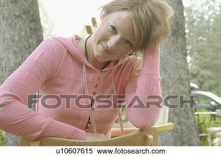 Young woman sits backward on chair at outdoor restaurant, Wasagaming, Riding Mountain National Park, Manitoba, Canada View Large Photo Image Stock Photography - Young woman sits backward on chair at outdoor restaurant, Wasagaming, Riding Mountain National Park, Manitoba, Canada. Fotosearch
