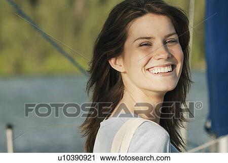 Stock Image - Young woman wearing hemp shirt, with hemp carry bag over her shoulder on sailboat, Clear Lake, Riding Mountain National Park, Manitoba, Canada. Fotosearch