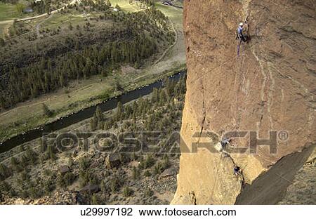 Stock Image - A group of men rock climbing on a free standing tower of rock., Smith Rock State Park, Terrebonne, Oregon, USA. Fotosearch