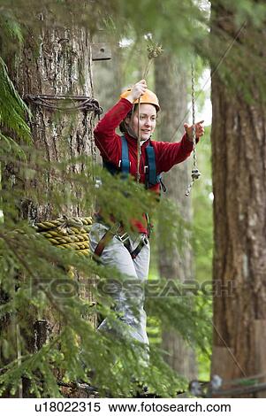 Stock Photography - A woman works her way through a high ropes course at the Strathcona Park Lodge, BC. Fotosearch