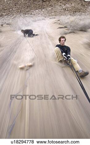 Two men (20-30) surfing behind a car on a dirt road, Bishop, California, USA View Large Photo Image Stock Photo - Two men (20-30) surfing behind a car on a dirt road, Bishop, California, USA. Fotosearch