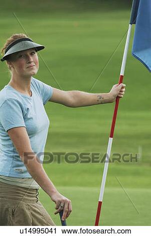 Stock Image - Woman on putting green, wearing hemp shirt, organic golf course, Clear Lake Golf Course, Riding Mountain National Park, Manitoba, Canada. Fotosearch