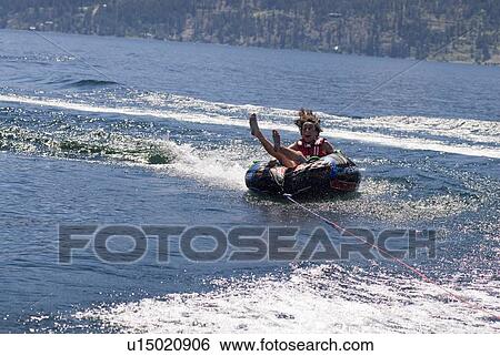 Young woman on inner tube behind boat, Okanagan Centre, BC Canada View Large Photo Image Stock Photograph - Young woman on inner tube behind boat, Okanagan Centre, BC Canada. Fotosearch