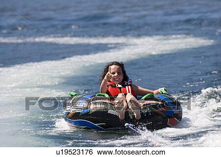 Young woman on inner tube behind boat, Okanagan Centre, BC Canada View Large Photo Image Stock Photograph - Young woman on inner tube behind boat, Okanagan Centre, BC Canada. Fotosearch