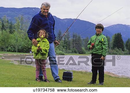 Stock Photo - Grandfather fishes with grandkids by lake, Whistler, BC. Fotosearch