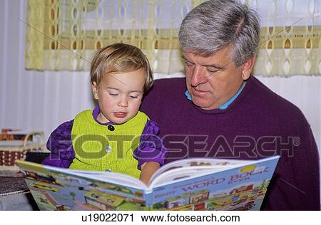 Stock Image - Grandfather reads to grandson, Kelowna, BC. Fotosearch