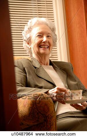 Picture - Senior Woman in Library with Tea; Canada, Saskatchewan, Regina. Fotosearch
