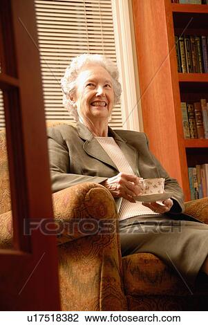 Stock Image - Senior Woman in Library with Tea, Regina, Saskatchewan. Fotosearch