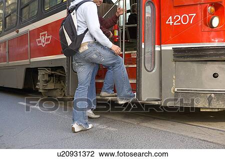 Stock Image - Passengers getting on electric Streetcar, Toronto Transit System, no carbon emissions; Canada, Ontario, Toronto. Fotosearch