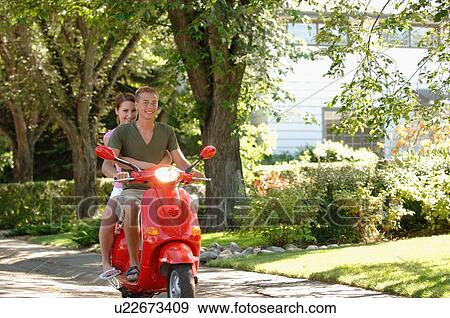 Stock Photo - Teenage boy and girl driving red vespa, Regina, Saskatchewan. Fotosearch