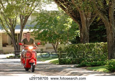 Stock Photography - Teenage boy and girl driving red vespa, Regina, Saskatchewan. Fotosearch