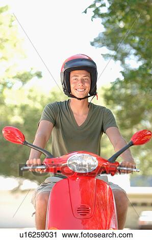 Stock Image - Teenage boy driving red vespa, Regina, Saskatchewan. Fotosearch