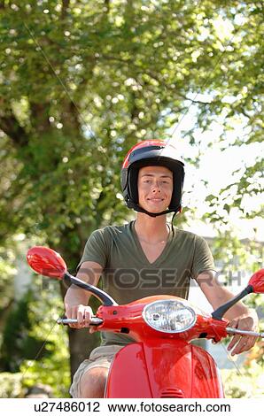 Stock Image - Teenage boy driving red vespa, Regina, Saskatchewan. Fotosearch