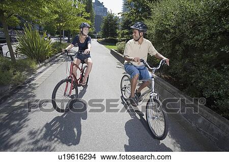 Picture - Young Couple Ride Bicycles on city bike path, Vancouver, British Columbia. Fotosearch
