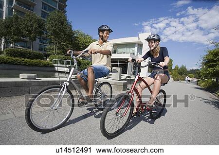 Stock Image - Young Couple Ride Bicycles on city bike path, Vancouver, British Columbia. Fotosearch