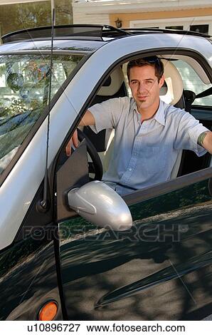 Young man sitting in smart car in front of house, Regina, Saskatchewan View Large Photo Image Stock Photo - Young man sitting in smart car in front of house, Regina, Saskatchewan. Fotosearch