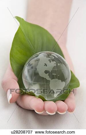 Stock Photo - a hand with a globe on the leaf. Fotosearch