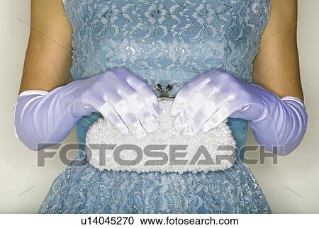 Stock Image - Gloved hands hold white handbag. Fotosearch