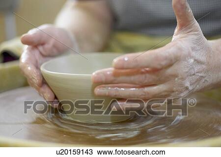 Stock Image - Hands molding a piece of pottery on a wheel-head, Burlington, Ontario. Fotosearch