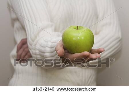 Stock Photograph - Woman holding organic apple out in front of her. Fotosearch