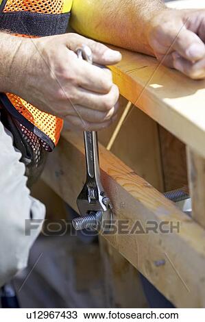 Stock Image - Worker tightening a nut with a wrench; Canada, Ontario, Hamilton (Composting Facility). Fotosearch