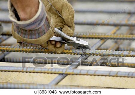 Stock Image - Workers gloved hands tying rebar with pliers and metal wire; Canada, Ontario, Hamilton (Composting Facility). Fotosearch