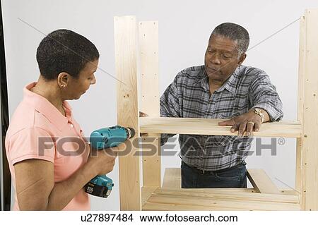 Picture - African American Couple Doing Home Improvement, Assembling a Shelving Unit, Canada, British Columbia. Fotosearch