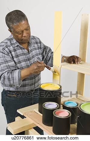 Stock Image - African American Man Doing Home Improvement Painting, Canada, British Columbia. Fotosearch