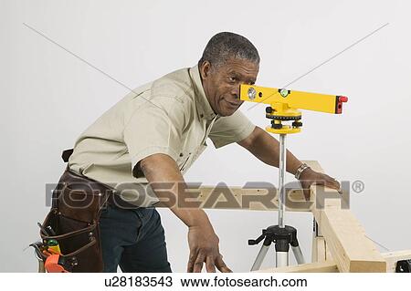 Stock Image - African American Man Doing Home Improvement, Using Laser Level, Vancouver, BC. Fotosearch