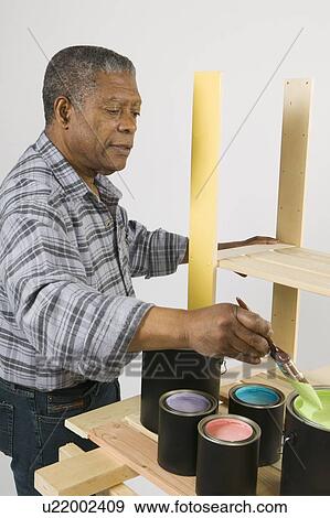 Stock Photo - African American Man Doing Home Improvement Painting, Canada, British Columbia. Fotosearch