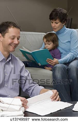 Man folds cloth diapers while woman and child read book on sofa, Winnipeg, Canada View Large Photo Image Stock Photo - Man folds cloth diapers while woman and child read book on sofa, Winnipeg, Canada. Fotosearch