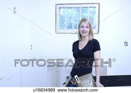 Stock Photo - Portrait of female contractor installing cupboards. Fotosearch