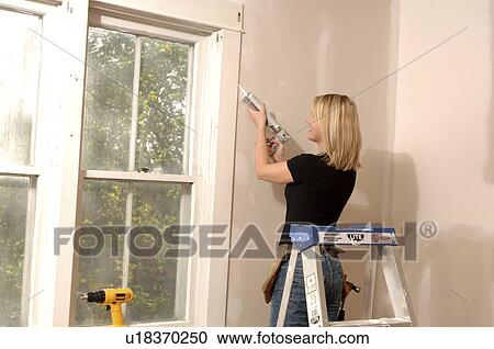 Woman putting caulking around window View Large Photo Image Stock Image - Woman putting caulking around window. Fotosearch